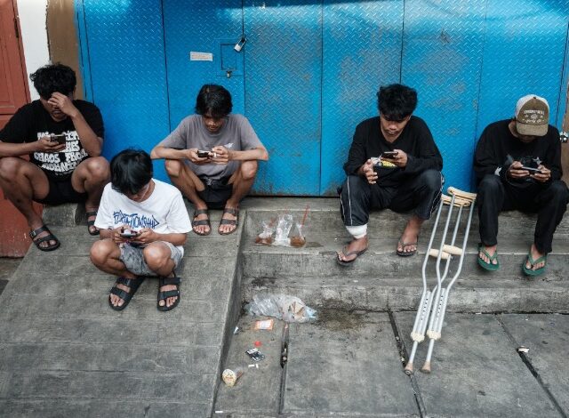Jóvenes indonesios usando teléfonos móviles antes de la prohibición de redes sociales para menores de 16 años.