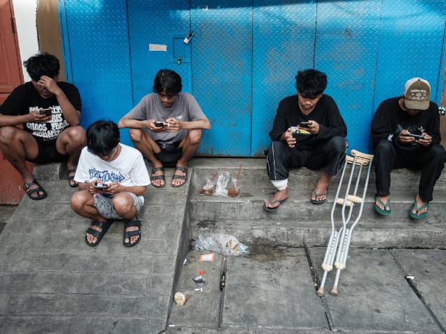 Jóvenes indonesios usando teléfonos móviles antes de la prohibición de redes sociales para menores de 16 años.