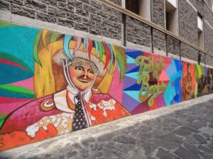 La imagen del chile en nogada, un tibor de talavera y un huehue de Xonaca son algunos de los elementos plasmados en el mural “Tributo al Barrio”, obra del artista Israel Jiménez Andrade, conocido como Foster.