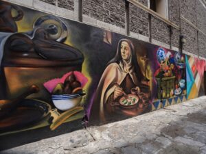 La imagen del chile en nogada, un tibor de talavera y un huehue de Xonaca son algunos de los elementos plasmados en el mural “Tributo al Barrio”, obra del artista Israel Jiménez Andrade, conocido como Foster.